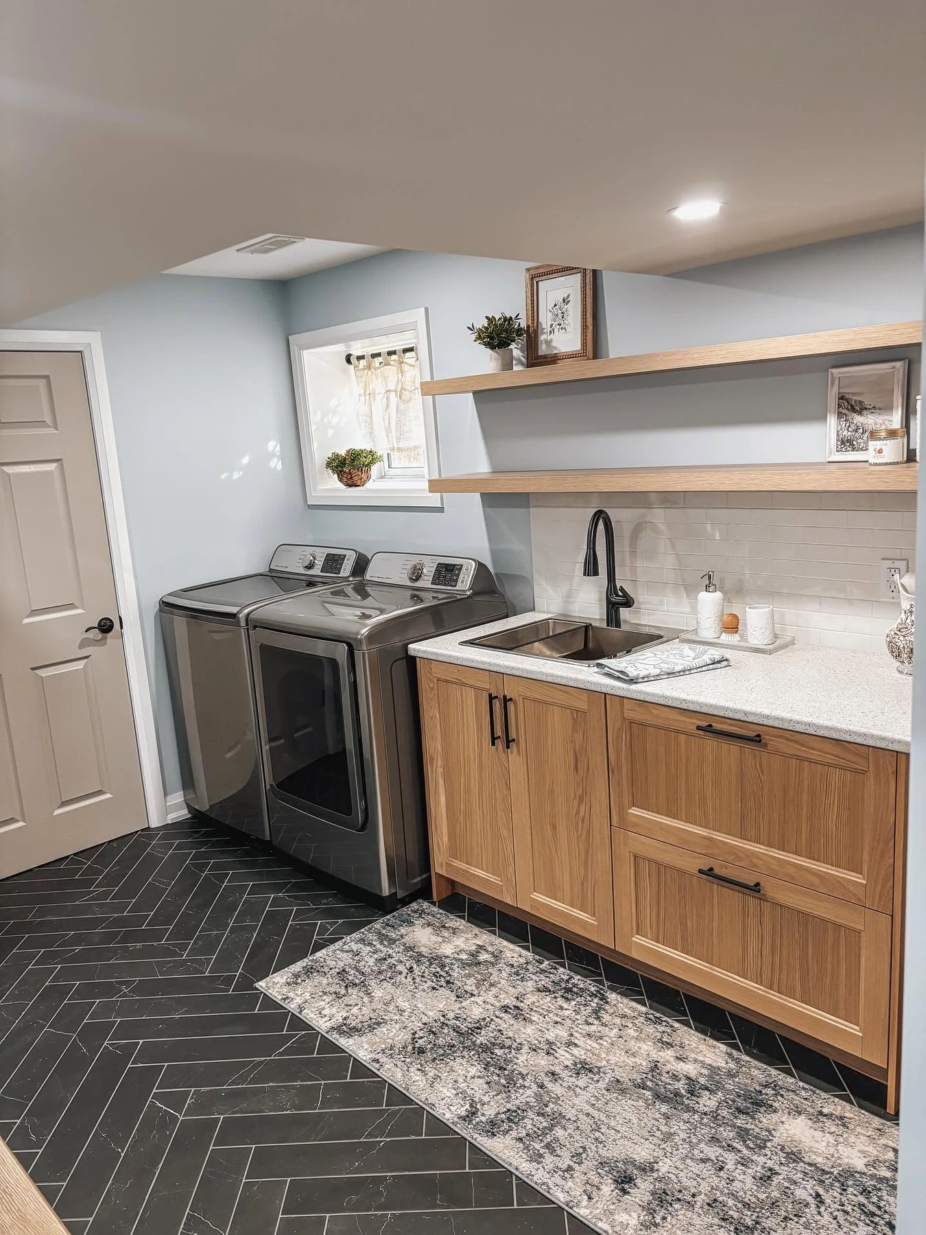 Finished basement laundry with oak cabinetry and herringbone tile