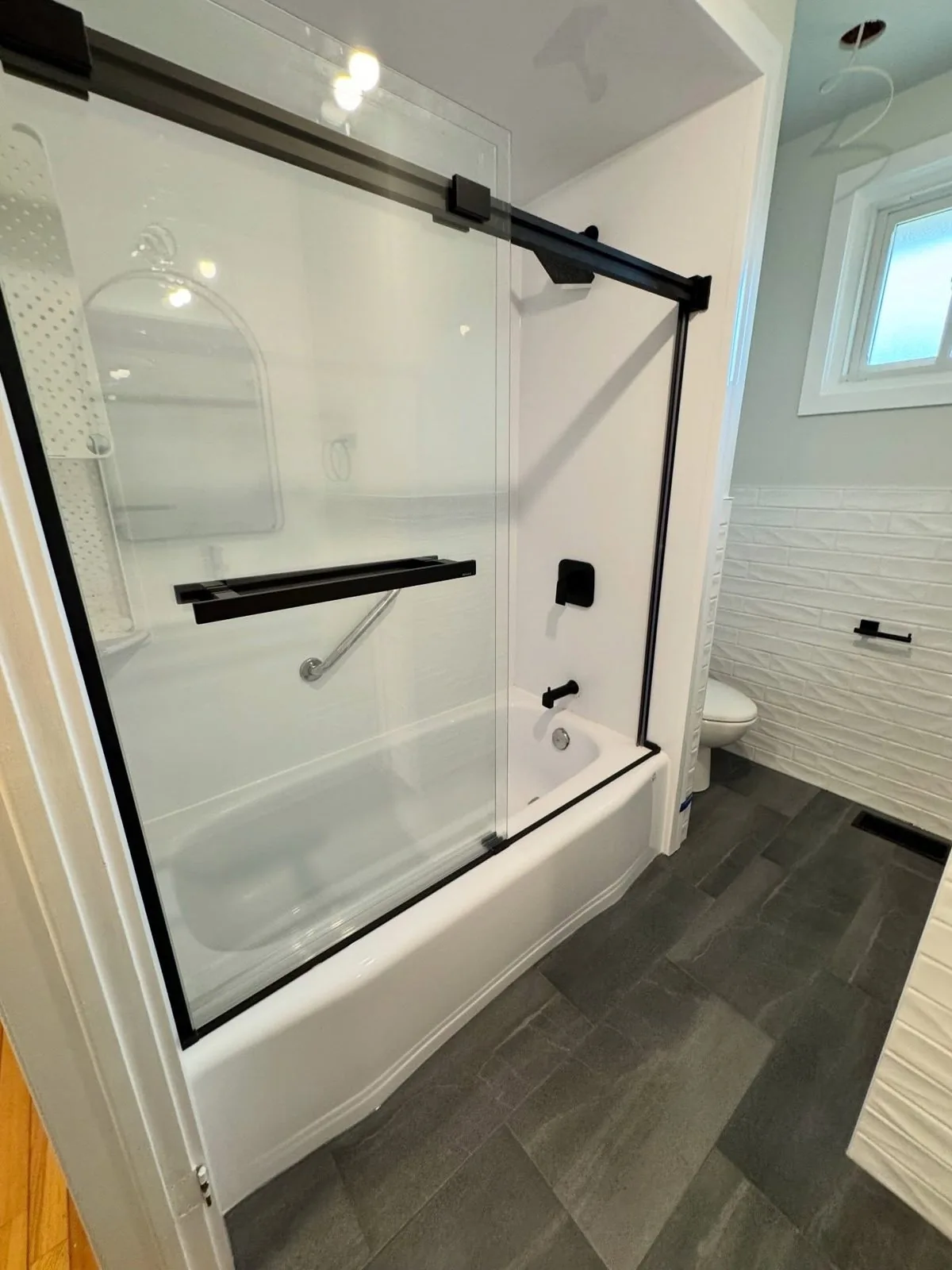 Tub and shower with black framed sliding glass