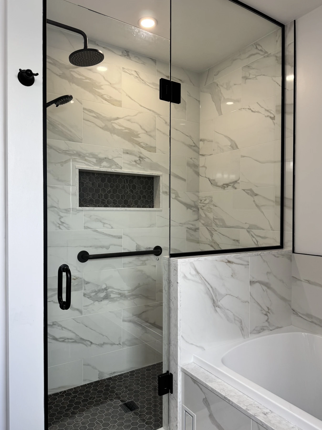 Shower in marble look porcelain behind black framed glass
