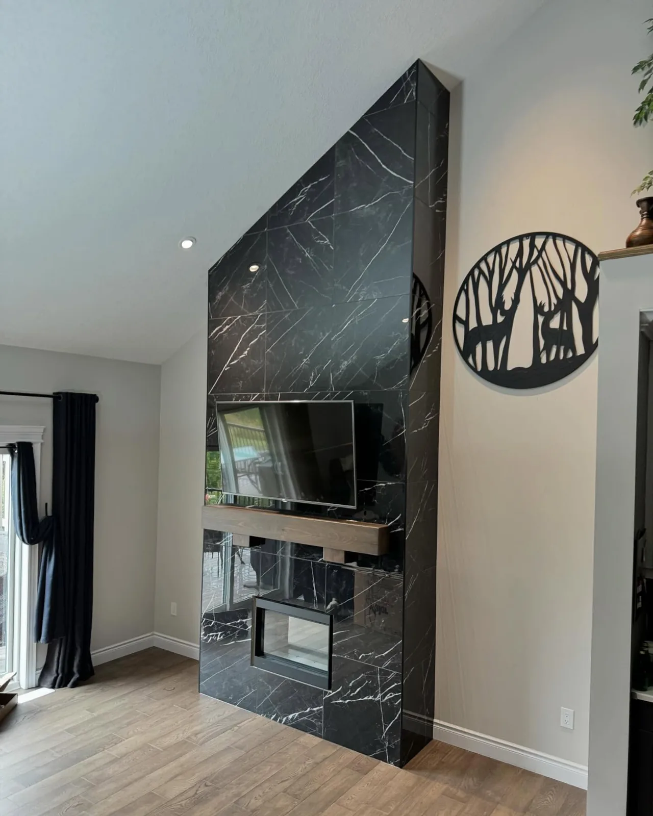 Black marble-look fireplace surround run floor to ceiling, with a timber mantel over a see-through firebox