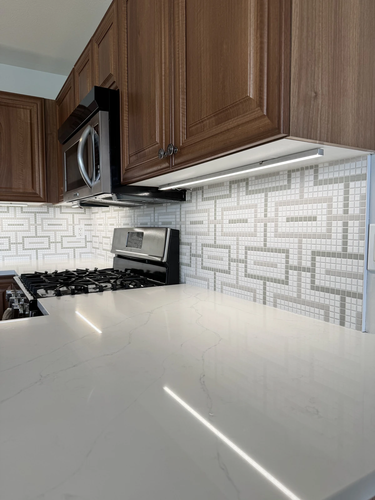White geometric mosaic backsplash above a quartz counter
