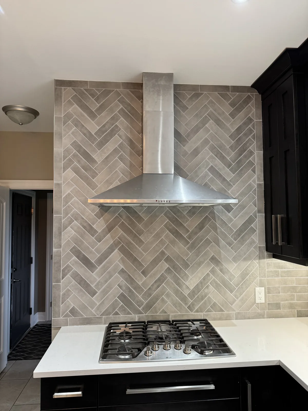 Herringbone tiled range wall with a stainless chimney hood