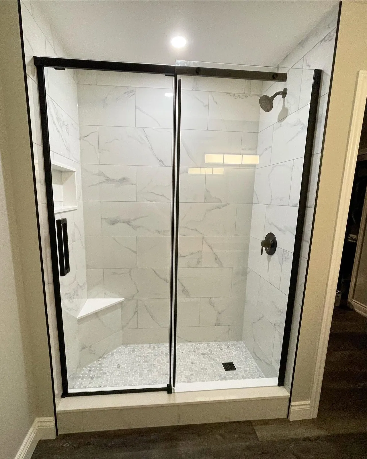 The finished shower behind black framed sliding glass