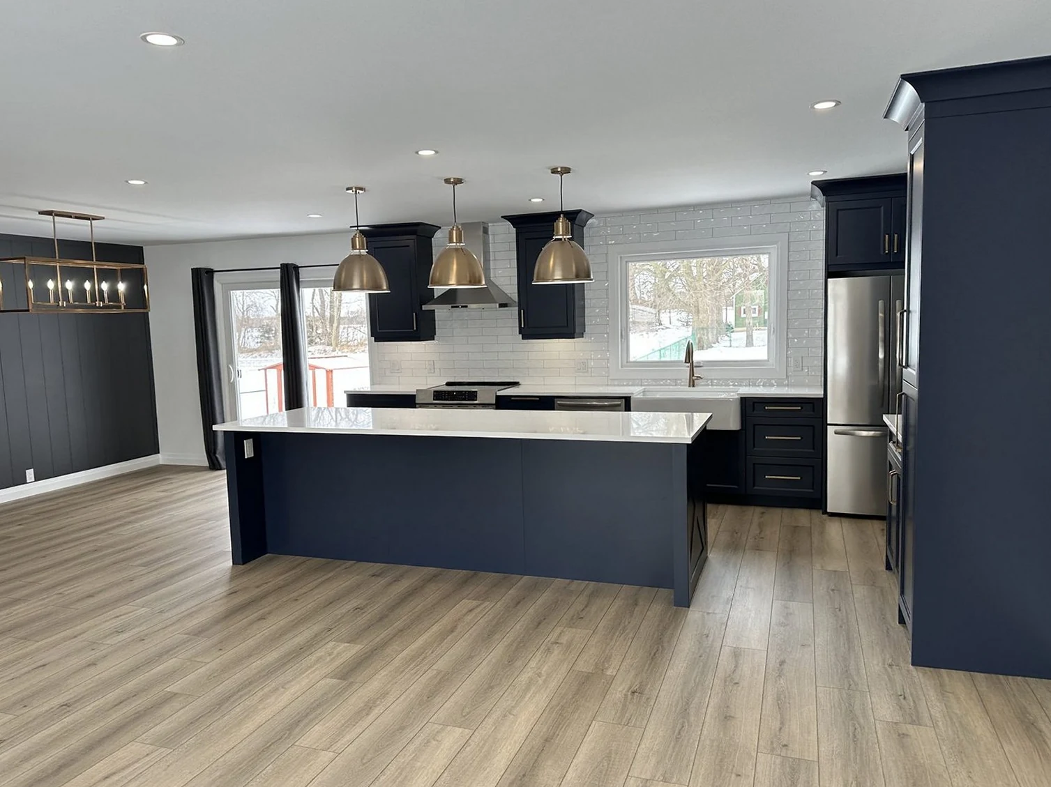 Finished navy kitchen with an island and brass pendant lights