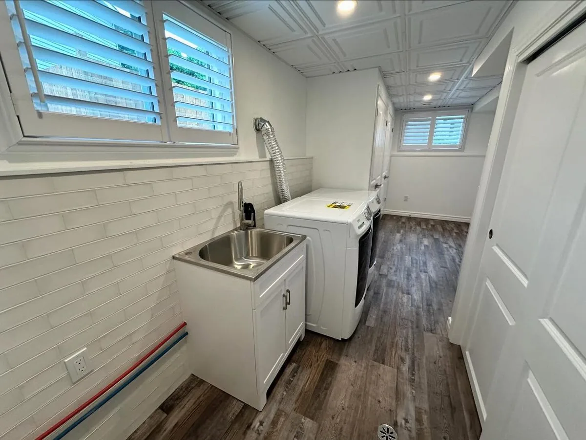 Finished basement laundry with tiled backsplash and coffered ceiling