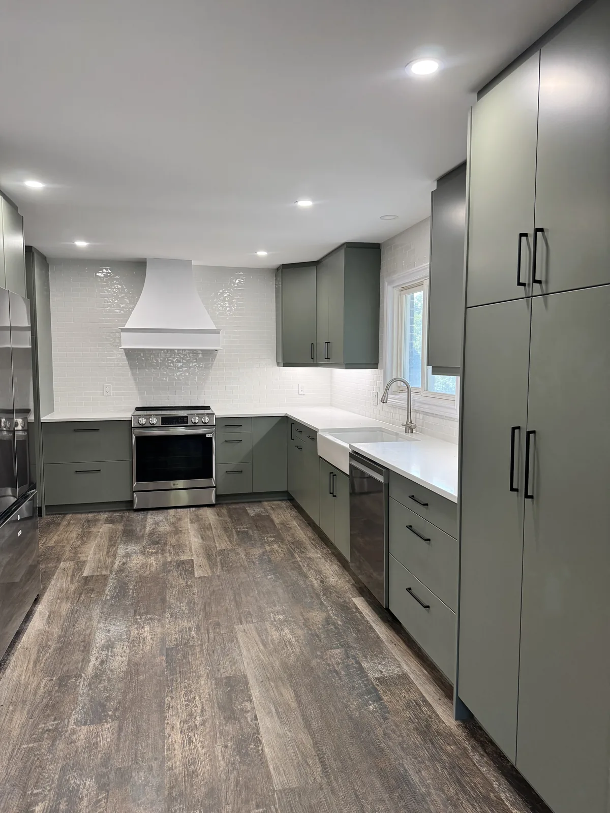 Sage green kitchen looking down the run to the range and hood