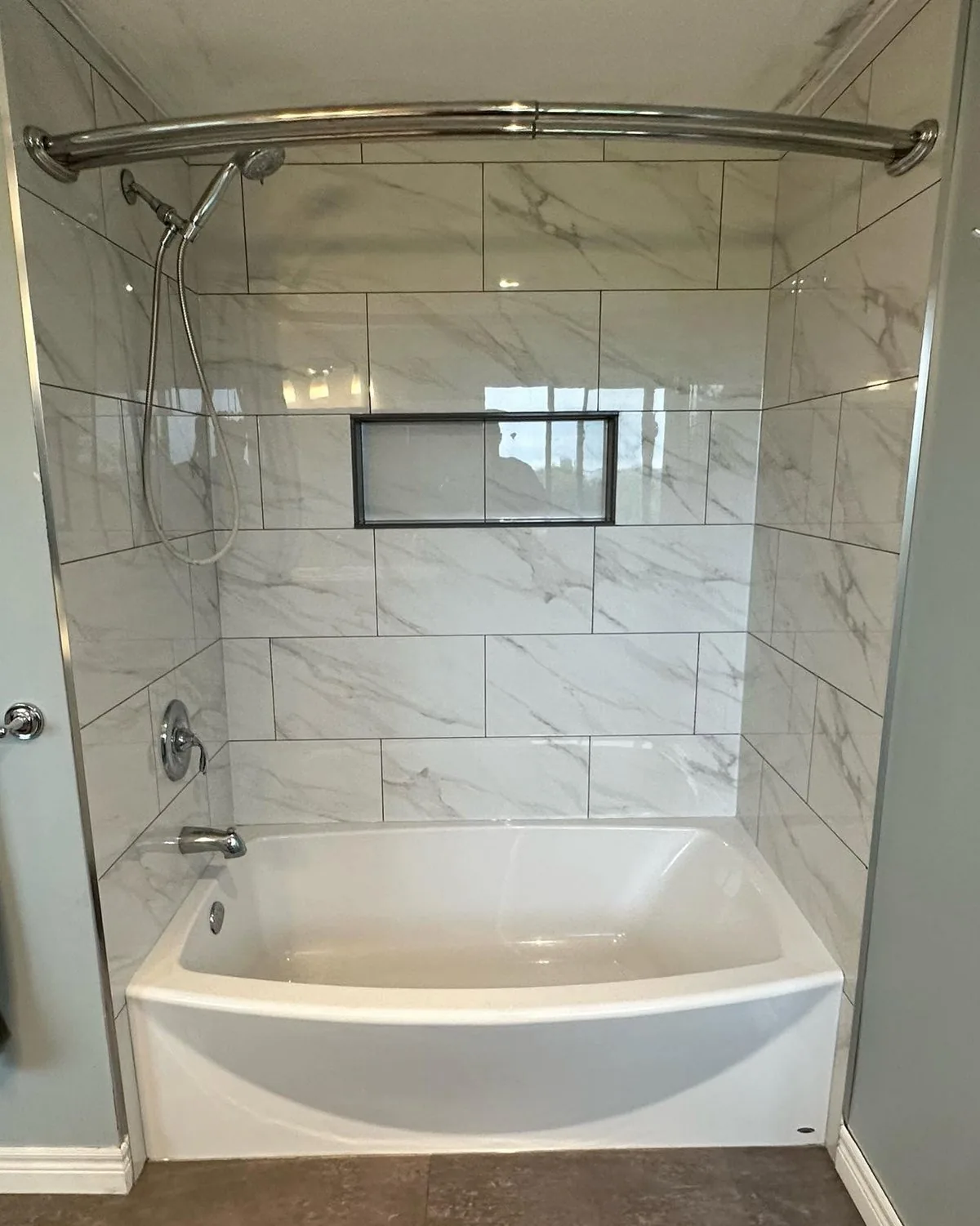 Tiled tub surround in marble-look large format with a recessed niche