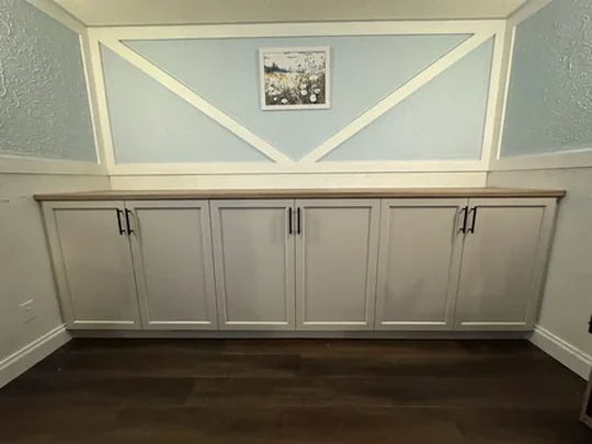 Painted cabinet run below a cross-braced panelled wall