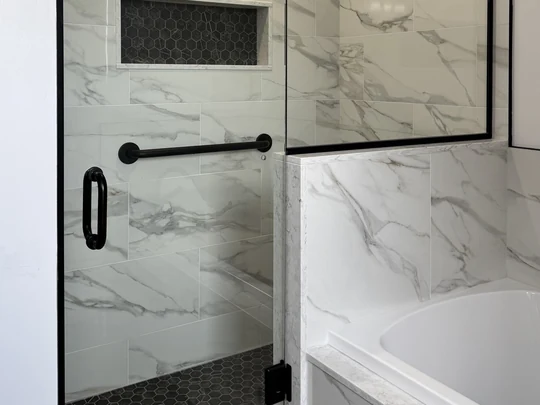 Marble-look shower behind black framed glass