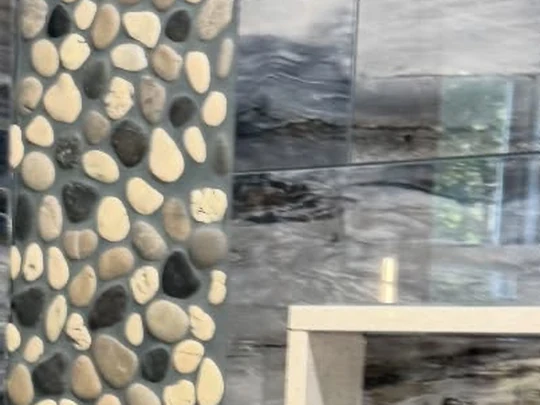Pebble mosaic strip run floor to ceiling beside a window