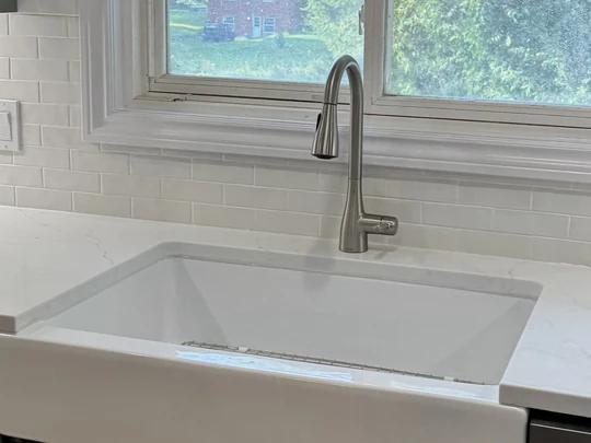Fireclay apron sink under a window with a brass tap