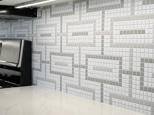 Geometric mosaic backsplash close up behind a gas range