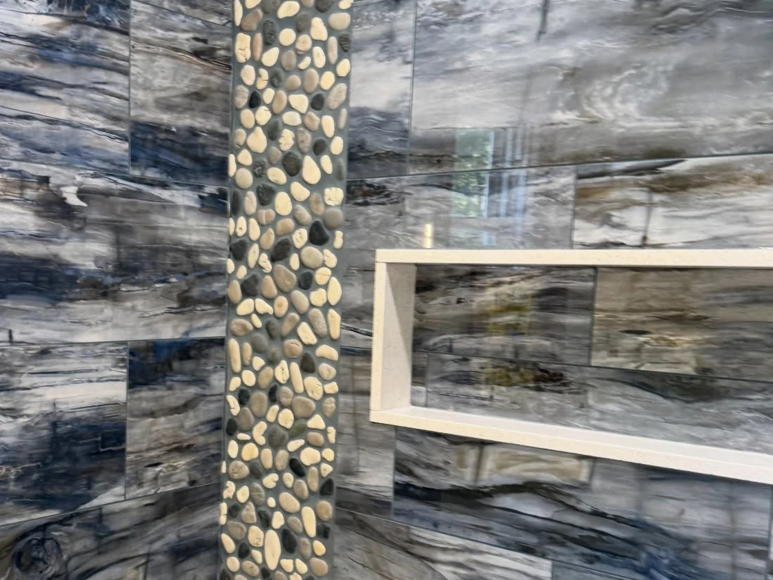 Marble-look porcelain with a pebble mosaic feature strip run floor to ceiling